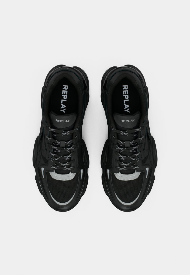 Baskets noires en mesh et en matériau synthétique, dotées d'une semelle épaisse, d'accents gris contrastants et d'une marque bien visible sur la languette.