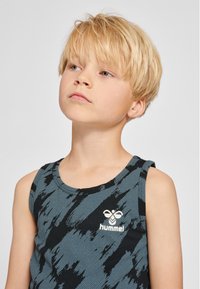 Zwart-blauw mouwloos tanktop met abstract gestreept patroon en een wit logo op de borst. Zachte stof, comfortabele pasvorm, ronde halslijn.