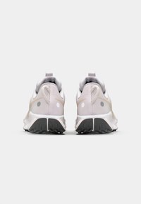 Chaussures de sport gris clair avec un dessus en tissu texturé, des accents réfléchissants et une semelle extérieure en caoutchouc noir. Présente un design minimaliste.