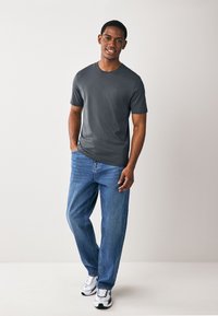 Grijs T-shirt met korte mouwen gemaakt van katoen, gecombineerd met een blauwe spijkerbroek. Heeft een klassieke pasvorm en een eenvoudig ontwerp zonder patronen.