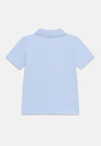 Ανοιχτό μπλε κοντομάνικο πόλο με κλασικό γιακά, υφασμάτινη υφή και μικρή διακοσμητική λωρίδα σε σχήμα V στην πλάτη.