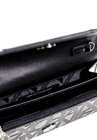 Borsa a tracolla in pelle nera con un esterno a motivo geometrico, accessori in metallo argentato e un interno liscio con logo impresso.
