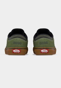 Ζεύγος πράσινων πάνινων παπουτσιών Vans από σουέντ με καφέ λαστιχένιες σόλες, ορατές μαύρες ραφές και «66/99» χαραγμένο στη φτέρνα.