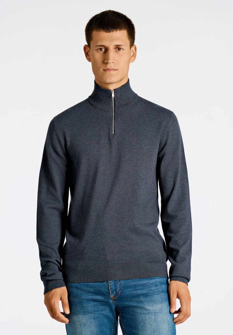 Czarny sweter w ciemnoszarym kolorze z wysokim kołnierzem i srebrnym zamkiem. Wykonany z miękkiej dzianiny, z prążkowanymi mankietami i dołem. Noszony z niebieskimi dżinsami.