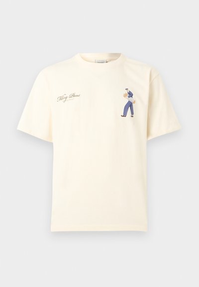 Κρεμ κοντομάνικο μπλουζάκι με μικρό γραφικό ενός ατόμου που κρατάει δύο μπαγκέτες και καλλιγραφικό κείμενο "Filling Pieces" στο στήθος.