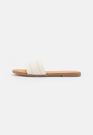 White woven slide sandal with braided texture and decorative beads, featuring a smooth tan footbed and flat rubber sole.