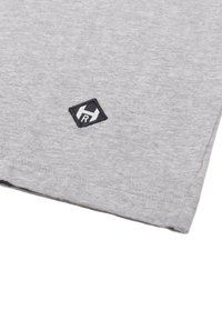 Grå bomulds t-shirt med rund halsudskæring, med et lille sort broderet logo i diamantform på den nederste venstre side.
