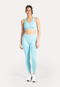 Top atletico azzurro chiaro con texture a coste e leggings a vita alta abbinati; tessuto liscio, design aderente e senza motivi visibili.