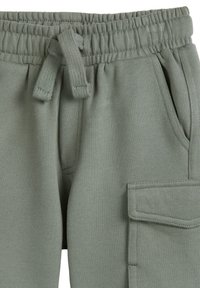 Hellgrüne Fleece-Jogginghosen mit einem elastischen Bund, Kordelzug, Seitentaschen und einer großen Cargotasche am rechten Bein.