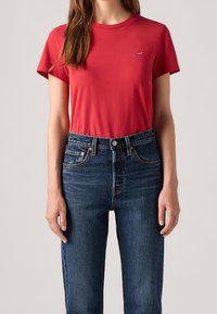 Czerwona bawełniana koszulka z krótkim rękawem, okrągłym dekoltem i małym logo Levi's. W połączeniu z ciemnoniebieskimi jeansami z wysokim stanem.