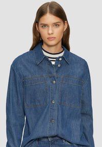 Jeansjacke in mittlerem Blau, mit Knopfleiste, zwei Brusttaschen und klassischem Kragen. Weicher Stoff, lässiges Design.