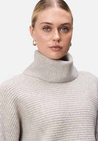 Hellgrau gerippter Strickpullover mit einem weichen Textur, ausgestattet mit einem hohen Kragen und einer lässigen Passform.