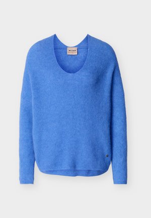 Modro dolg rokav pleten pulover z okrolim izrezom in majhno kovinsko značko z logotipom blizu roba na enobarvnem ozadju.