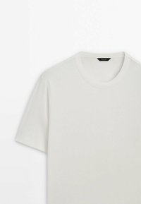 T-shirt blanc à manches courtes et col rond, présenté à plat sur un fond blanc avec une étiquette noire visible à l’intérieur du col.