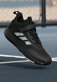 Czarny but sportowy z siateczkowym wierzchem, białymi poziomymi paskami i paskiem na rzep. Posiada teksturowaną gumową podeszwę zapewniającą przyczepność.