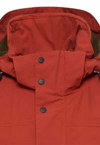 Nahaufnahme der roten Jacken-Kapuze mit drei schwarzen Druckknöpfen und braunem Netzbelüftung an den Seiten.