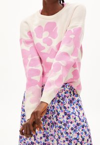 Rosa och krämfärgad stickad tröja med blommönster, rund halsringning och ribbade muddar, kombinerad med en flerfärgad blommig kjol.