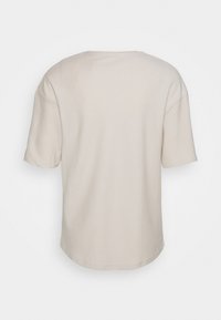 Beige T-Shirt mit kurzen Ärmeln und einem strukturierten diagonalen Muster. Rundhalsausschnitt und lockerer Schnitt, aus weichem Stoff gefertigt.