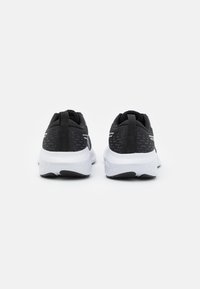 Black athletic shoes with a textured upper, white midsole, and black outsole. Features a looped heel tab and reflective accents.
