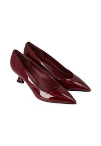 Escarpins vernis rouges à talon haut avec un bout pointu et un petit talon aiguille. Surface lisse et brillante avec une marque visible à l'intérieur.