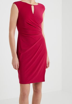 Robe rouge sans manches, longueur au genou, avec un détail froncé à la taille et une petite encolure en forme de goutte, fermée par un fermoir doré.