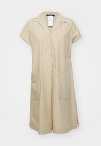 Robe beige à manches courtes avec col, poches à l'avant et coupe droite suspendue sur un fond blanc.