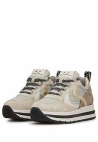 Zapatillas beige y gris con materiales mixtos, que incluyen ante texturizado, acentos brillantes, cordones en blanco y negro, y una suela rayada.