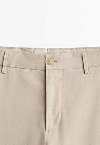 Beige broek met een gladde textuur, klassiek ontwerp, knoopsluiting en riemlussen aan de tailleband. Eenvoudige en veelzijdige styling.