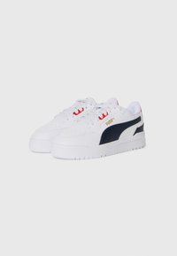 Sneaker atletiche bianche con una striscia laterale blu navy, dettagli rossi sui lacci e suola testurizzata. Presentano un dettaglio perforato sulla punta.