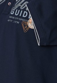 Marine polo-shirt met een gestructureerde stof, een kraag met twee knopen, en gedrukte graphics waaronder een kompas en locatiecoördinaten.