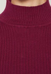 Bordó žebrovaný rolák z jemného texturovaného pleteného materiálu, se stojáčkem a vzorem s vertikálními pruhy.