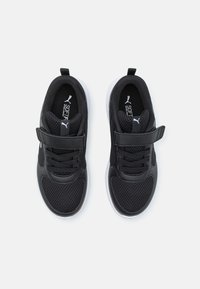 Baskets de sport noires avec une tige en mesh et en synthétique, dotées de lacets et d'une sangle, semelle blanche et éléments de design texturés.
