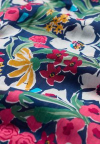 Blommig tyg med ett livfullt mönster med stora rosa, vita och gula blommor på en marinblå bakgrund. Mjuk textur, blandmaterial i bomull.