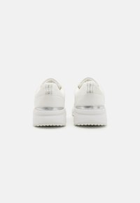 Weißes Sneaker-Modell mit einem Obermaterial aus glattem Leder, gepolstertem Kragen und einem silbernen Akzent an der Ferse. Dicke Gummisohle mit strukturiertem Profil.