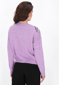 Suéter lila de corte relajado, con dobladillo acanalado y detalles decorativos de cuentas en los hombros, hecho de una suave tela texturada.