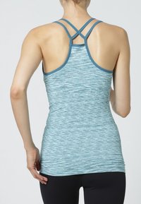 Jasnoniebieski sportowy top na ramiączkach z teksturowanym, paskowanym wzorem. Posiada cienkie regulowane ramiączka krzyżujące się z tyłu.
