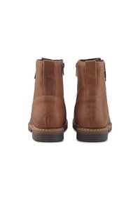 Par de botas de cuero marrón hasta el tobillo vistas desde atrás, con tacones apilados y costuras visibles a lo largo de los bordes de la suela.