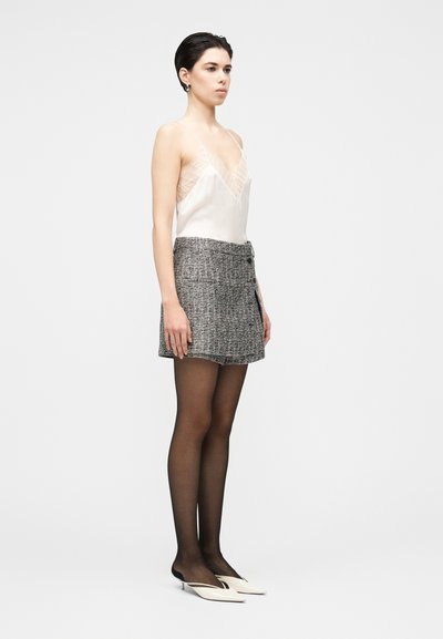 White satin camisole with lace trim paired with a gray tweed mini skirt, black tights, and pointed white heels. Simple, modern silhouette.