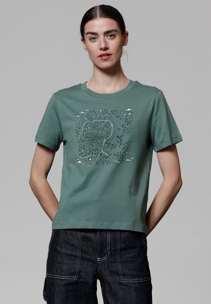 Groene katoenen t-shirt met een gedrukt landschapsontwerp van bergen, bomen en een kronkelige rivier. Korte mouwen en een ronde halslijn.