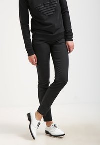 Svart sweatshirt med texturerat hjärtdesign och matchande svarta slim-fit byxor. Vita snörskor med svarta detaljer och en texturerad sula.