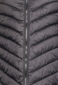 Gilet imbottito nero con motivo a zigzag, zip frontale con dettagli in argento e tessuto liscio e lucido.