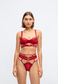 Red lingerie set featuring a padded bralette with floral lace detail, gold hardware accents, and a matching strappy thong with cutouts.