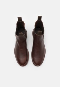 Botas tobilleras de cuero marrón con textura suave, paneles laterales elásticos y lengüetas de tirón; punta redondeada y detalle de suela cosida.