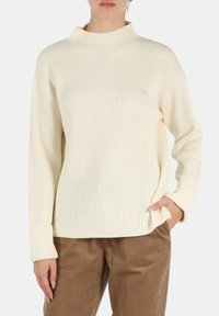 Maglione a collo alto a coste crema con maniche lunghe; presenta una vestibilità comoda e un piccolo logo sul petto. Texture morbida, design casual.