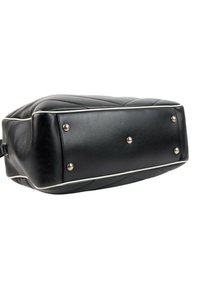 Fond d’un sac à main en cuir noir avec une bordure blanche et cinq pieds en métal argenté sur fond blanc.