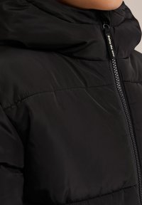 Černá péřová bunda s vysokým límcem, předním zipem a vodorovným prošíváním. Hladký povrch s lesklým finišem po celém výrobku.