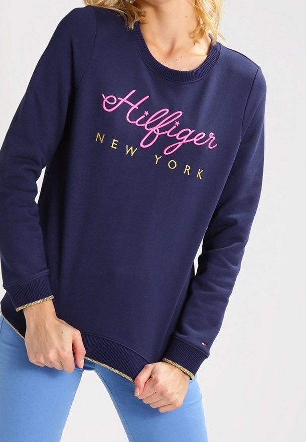 Sweat-shirt bleu marine avec "Hilfiger NEW YORK" en broderie rose et dorée. Équipé de poignets et d'ourlet côtelés avec des accents dorés contrastants.