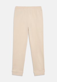 Μπεζ βαμβακερές φόρμες με ελαστική μέση, tapered πόδια και ριμπ μανσέτες. Λείο υφή με απλό, μονόχρωμο σχέδιο.