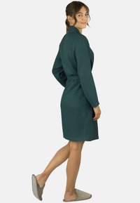 Türkisfarbener Waffelpique-Bademantel mit langen Ärmeln, tailliertem Gürtel und strukturierter Oberfläche. Praktische Seitentaschen und knielanges Design.