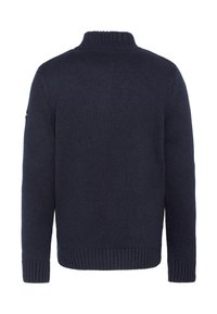 Pull en maille bleu marine avec un col montant, des poignets et un ourlet côtelés, présentant un tissu texturé et un petit logo sur la manche gauche.
